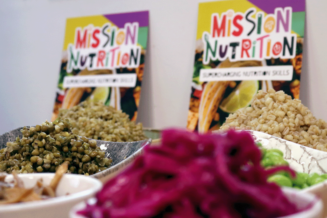 An image of nutritious bowls of ingredients with mission nutrition branded flyers propped up behind them