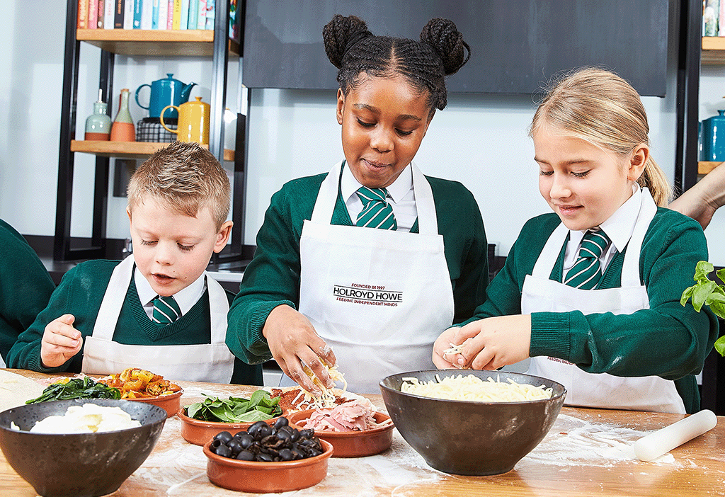 Bespoke catering services. Three children in green uniforms and aprons prepare food at a flour-covered table with various ingredients.