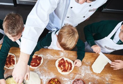 An image of a chef teaching pupils how to make pizza