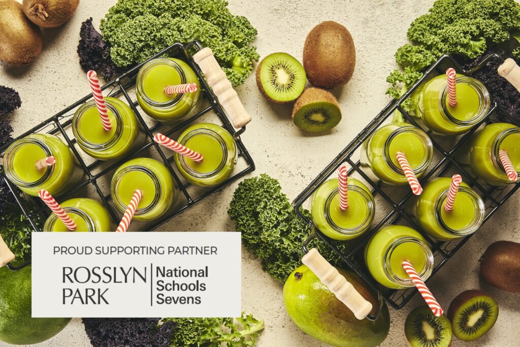 A selection of green kiwi smoothies in glass jars. In the bottom left corner, there is a logo with the text "Proud Supporting Partner Rosslyn Park National Schools Sevens."