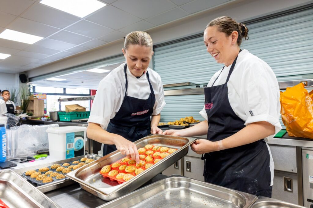 Home 33 Holroyd Howe chefs preparing trays of food in a school kitchen